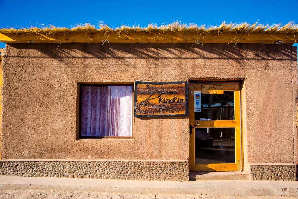 un edificio con una ventana y un cartel en él en Hostal Kirckir en San Pedro de Atacama