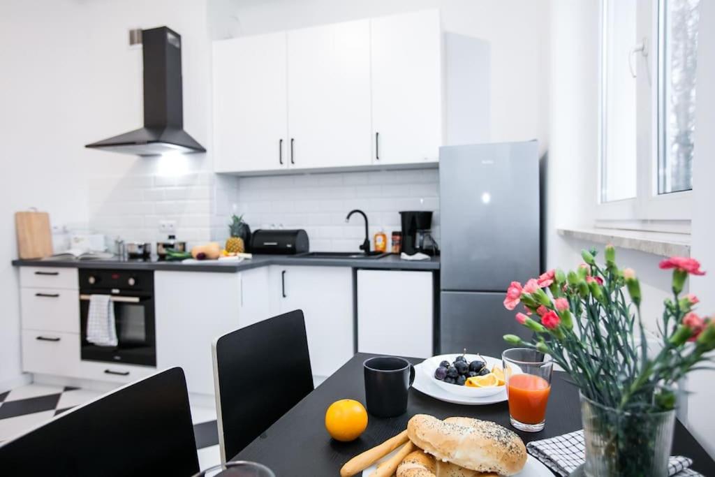 華沙的住宿－Cozy, fully equipped apartment in Mokotów district，厨房里配有一张桌子,上面有盘子的食物