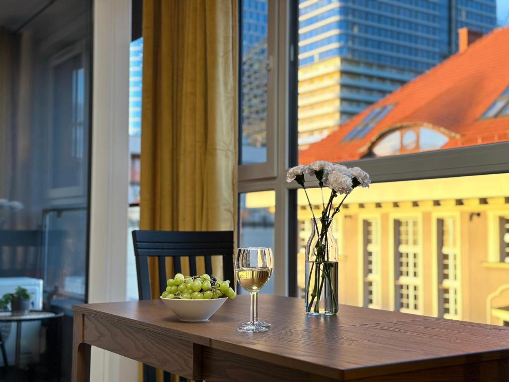 a table with a glass of wine and a bowl of grapes at URBAN APARTMENTS PREMIUM, Opolska 10 No 80, Free Garage, Self Check-in in Katowice