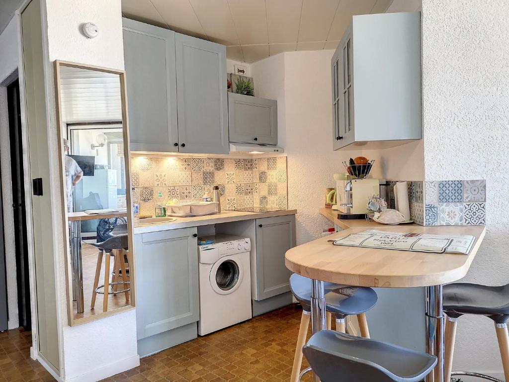 a small kitchen with white cabinets and a table at Appartement chic vue mer in Le Barcarès