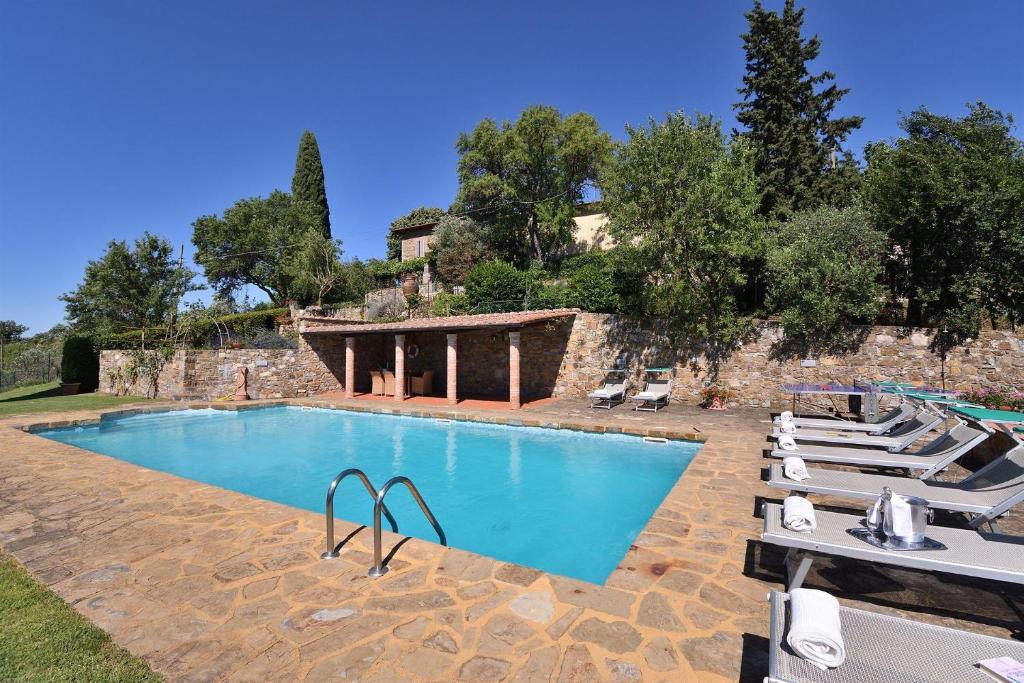 a large swimming pool with lounge chairs and a building at Casanovina in Castellina in Chianti