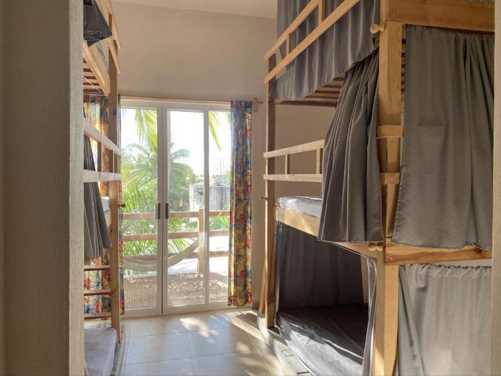 a room with two bunk beds and a balcony at La Palmera Hostel in Puerto Escondido