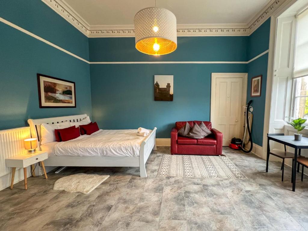 a bedroom with a bed and a red chair at Cozy Studio Apartment of Glasgows West End in Glasgow