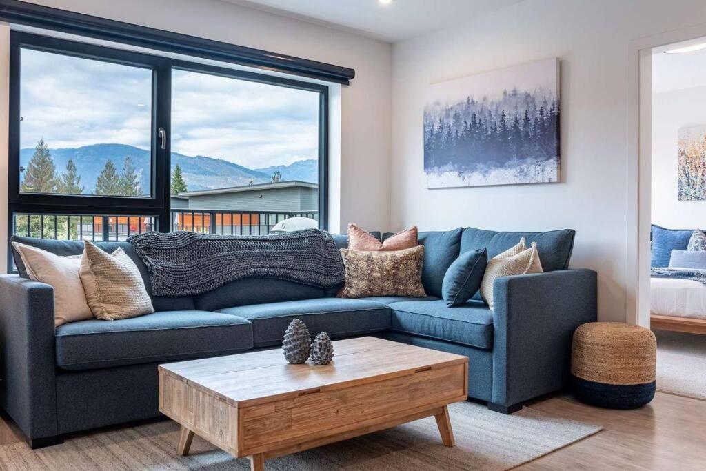 a living room with a blue couch and a table at Bluebird Daze by Revelstoke Vacations in Revelstoke