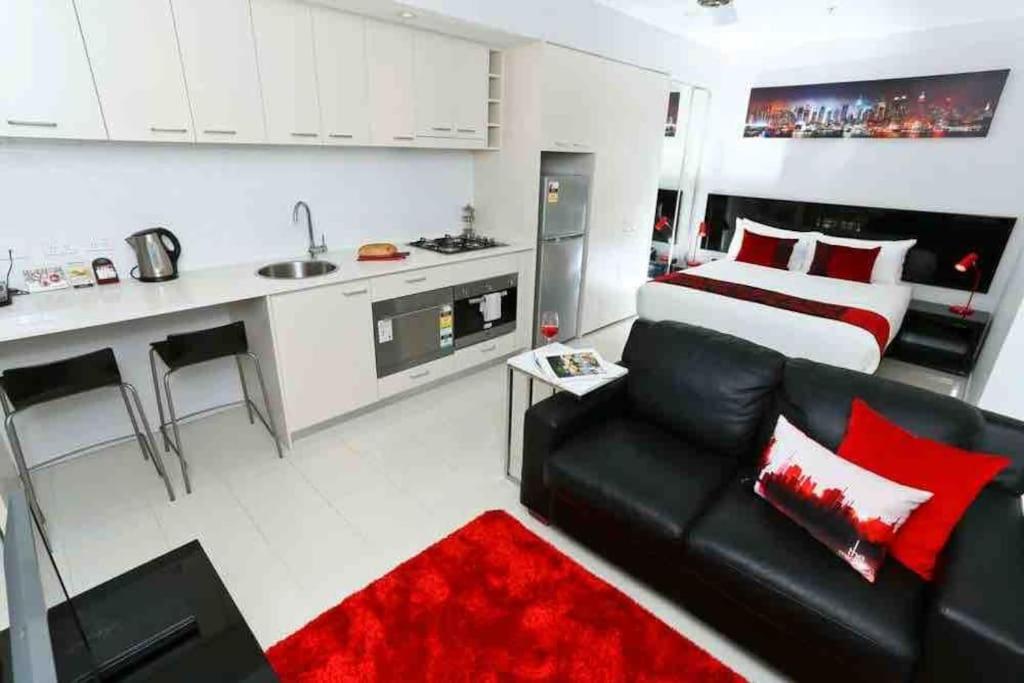 un soggiorno con divano nero e una cucina di Central CBD Studio, Balcony, Pool, Gym, Sauna a Brisbane