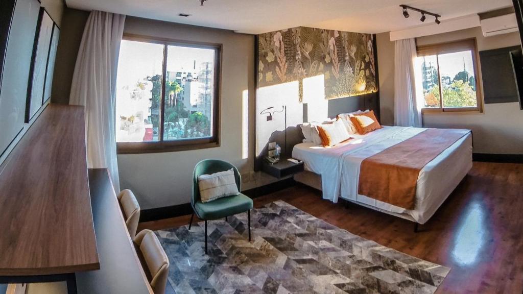 um quarto com uma cama, uma cadeira e janelas em Art Hotel Transamerica Collection em Porto Alegre