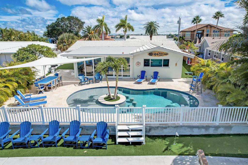 a swimming pool with blue chairs and a house at Fall Promo! Heated Pool, 6p Golf Cart, Kayak in Clearwater Beach