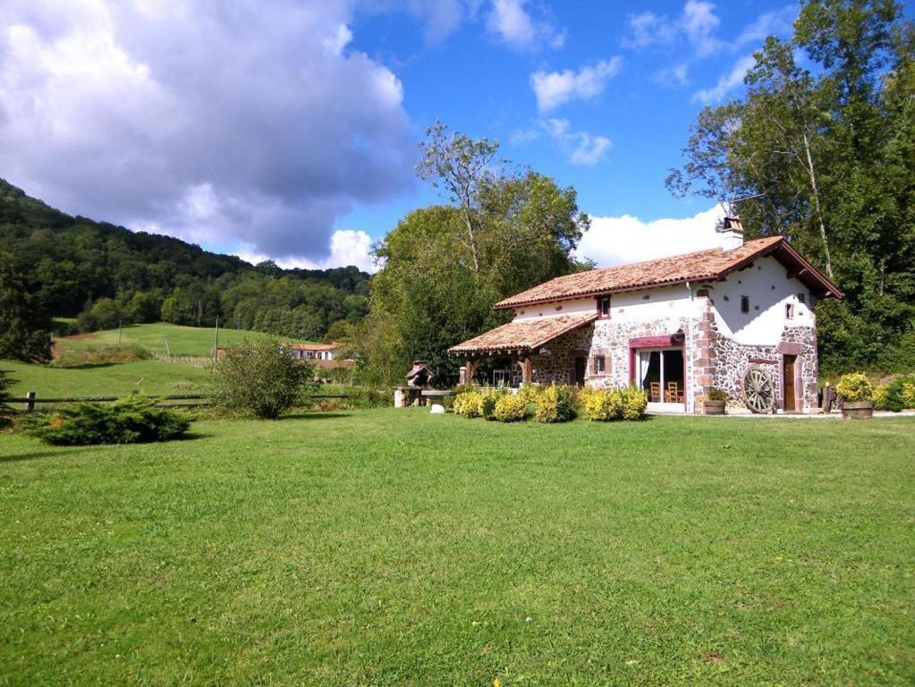 a stone house in a field with a grass yard at Gaztelia in Saint-Jean-le-Vieux