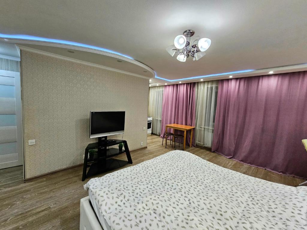 een slaapkamer met een bed en een flatscreen-tv bij Аpartment on Аbdiova in Karagandy