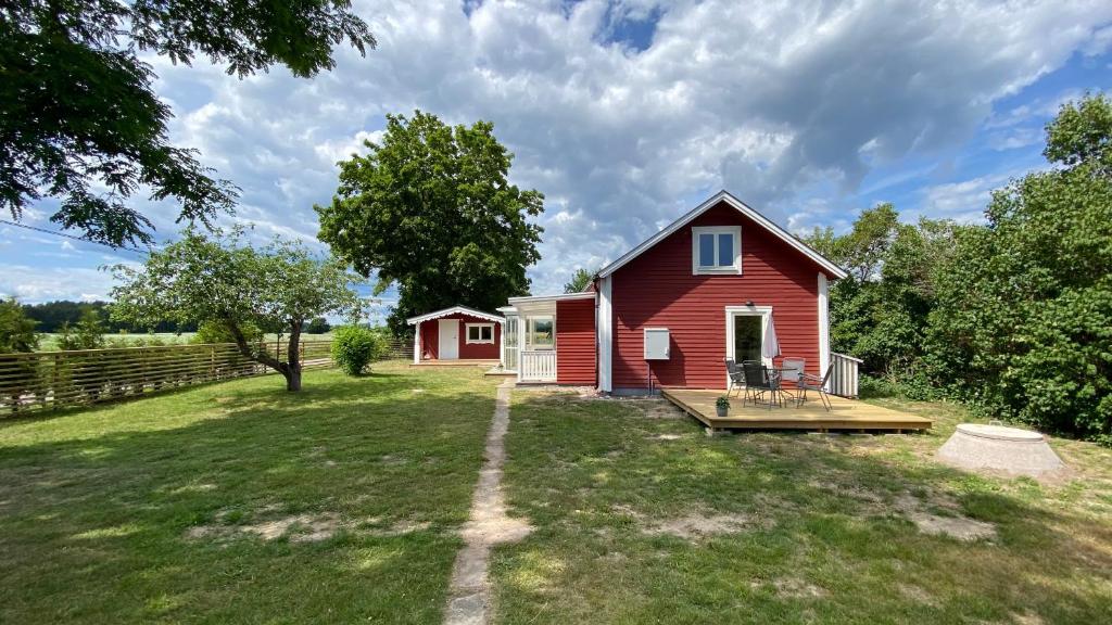 ein rotes Haus mit einer Terrasse im Hof in der Unterkunft Charmig, nyrenoverat och fullt utrustad stuga. Anpassad för hundar, nära till naturen och havet. Gångavstånd till golfbana. in Kalmar