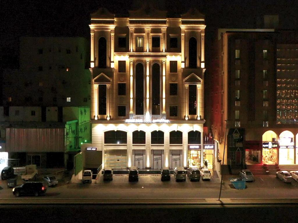 un edificio iluminado con coches estacionados frente a él en Violet rose, en Yeda