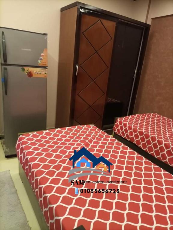 Zimmer mit einem Bett, einem Kühlschrank und einer Tür in der Unterkunft SAM real estate in Madinat as-Sadis min Uktubar