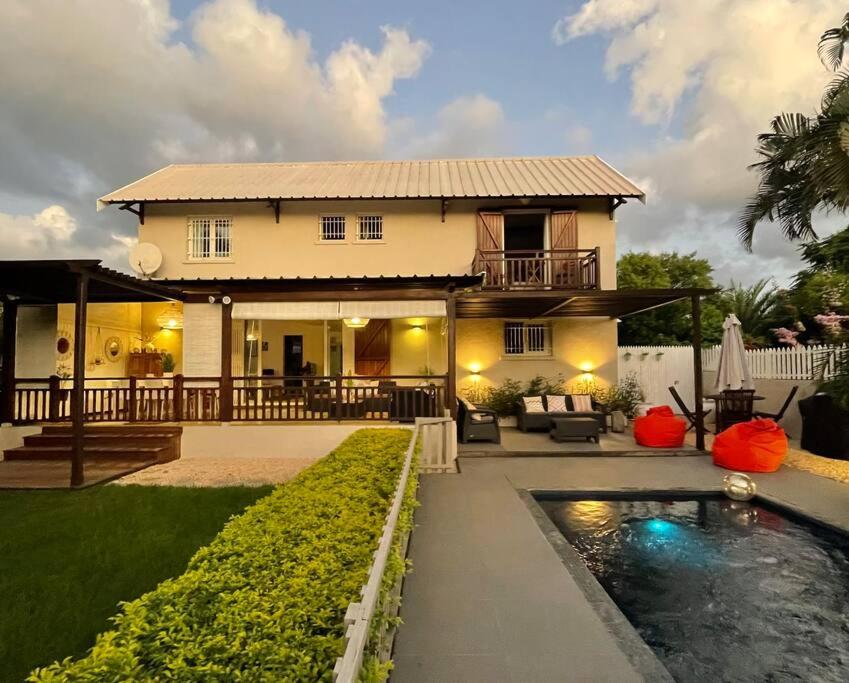 une maison avec une piscine en face d'une maison dans l'établissement Calme et Bien-Être « Villa Sous Le Manguier », à Rivière Noire