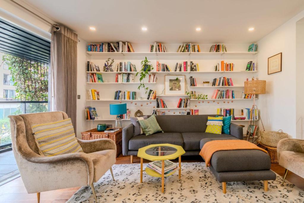 a living room with a couch and chairs and bookshelves at Beautiful Canal-side Flat in Hackney in London