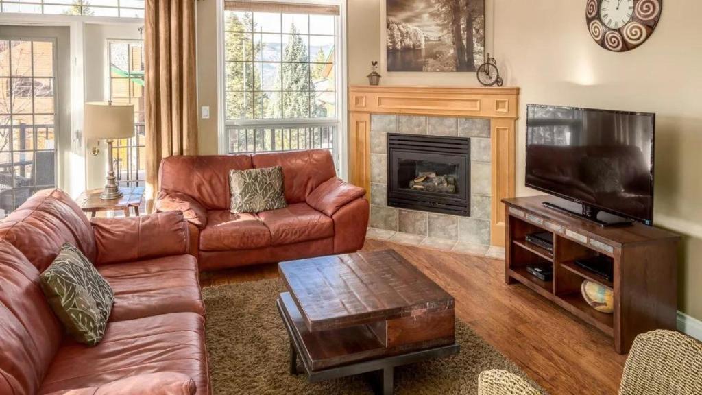 sala de estar con sofá de cuero y chimenea en Marble Canyon Townhouse, en Fairmont Hot Springs