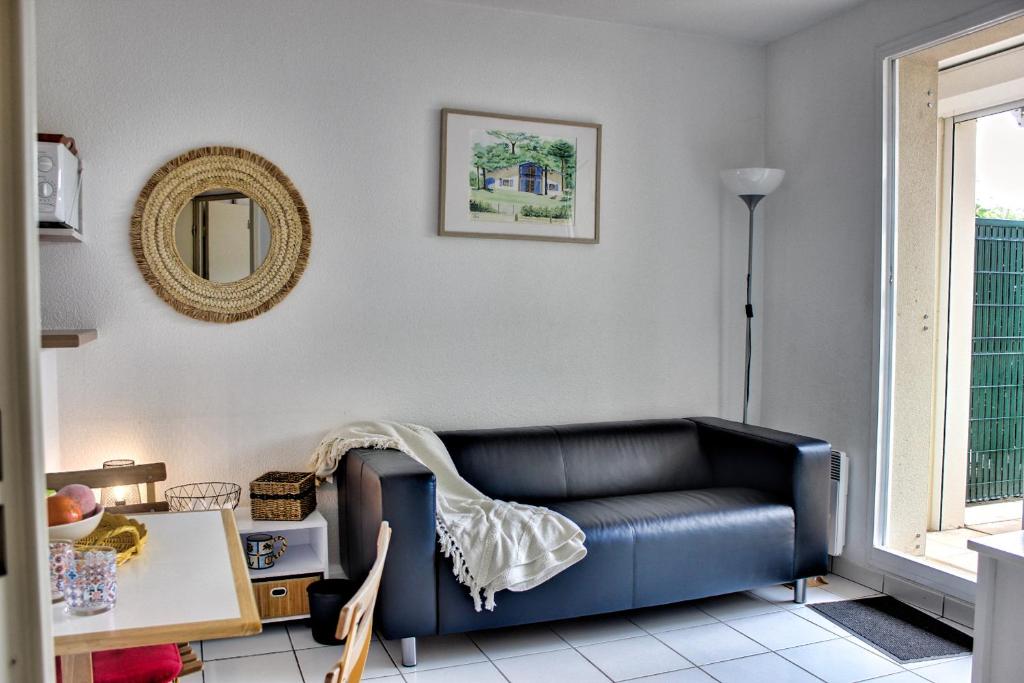 Bleu Pontaillac YourHostHelper في فو سور ميه: غرفة معيشة مع أريكة سوداء ومرآة