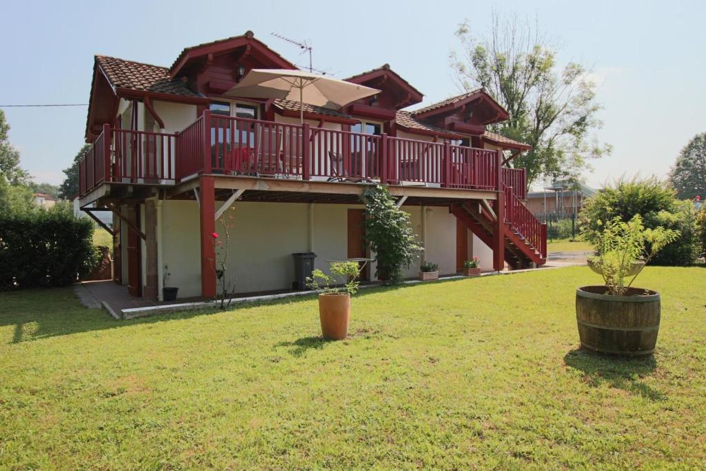 a house with a balcony and an umbrella in a yard at Le jai alai in Saint-Jean-Pied-de-Port