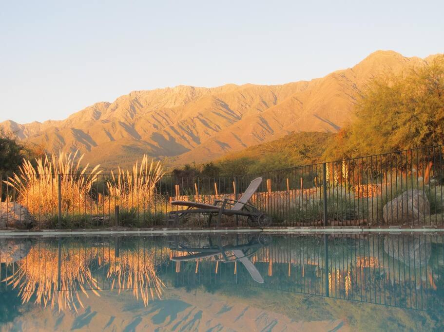 a bench sitting next to a body of water with mountains at Cabaña romántica en la sierra in Yacanto