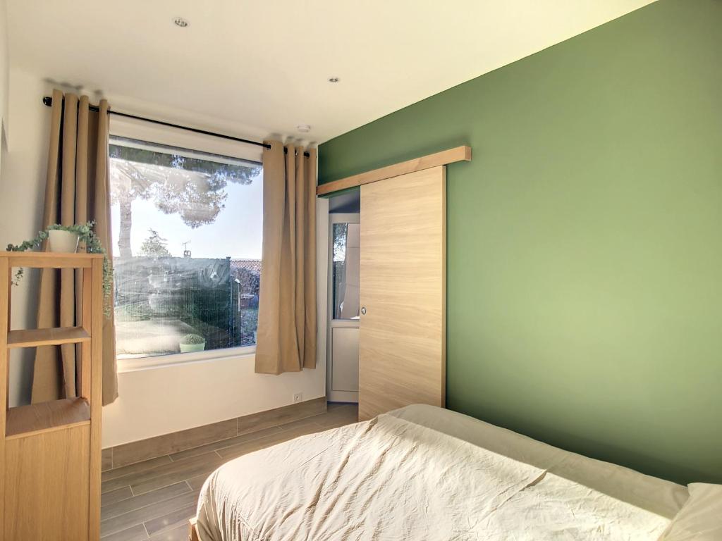 Schlafzimmer mit grünen Wänden und einem Bett mit Fenster in der Unterkunft Appartement aux salins du lion in Vitrolles