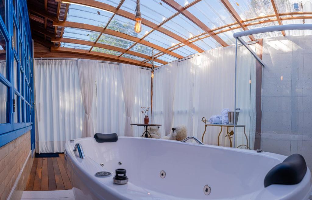 a large white tub in a room with a glass ceiling at Chales Labelle - 5 minutos do Centro e da Rodoviária de Santa Teresa in Santa Teresa