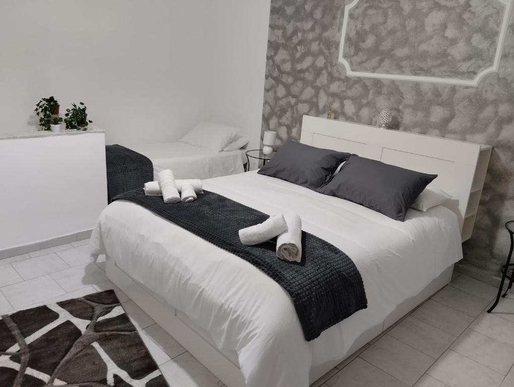 a bedroom with a large white bed with towels on it at House Lurokè in Catania