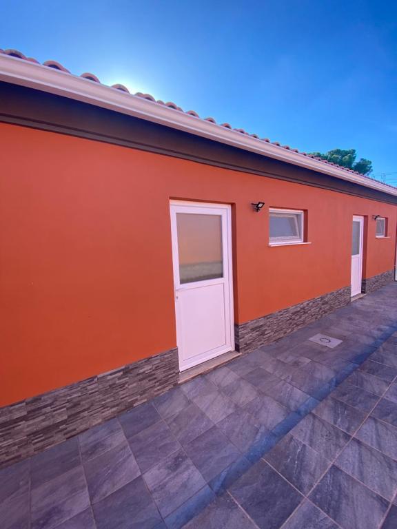 Un edificio naranja con una puerta blanca. en Casa dos Diogos en Grândola