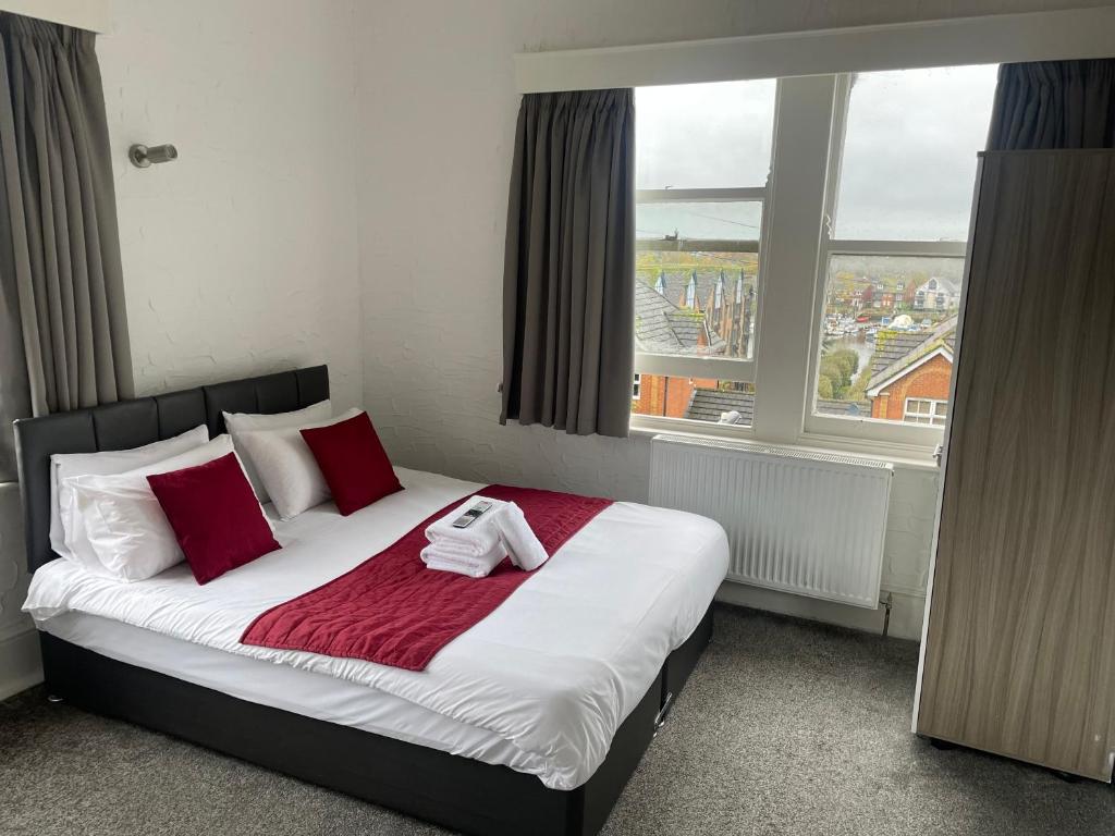 a bedroom with a bed with red pillows and a window at River side rooms in Southampton