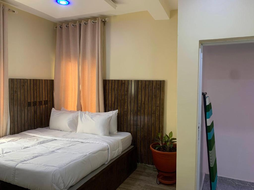 um quarto com uma cama com lençóis brancos e uma janela em Bott Extended Stay em Abuja