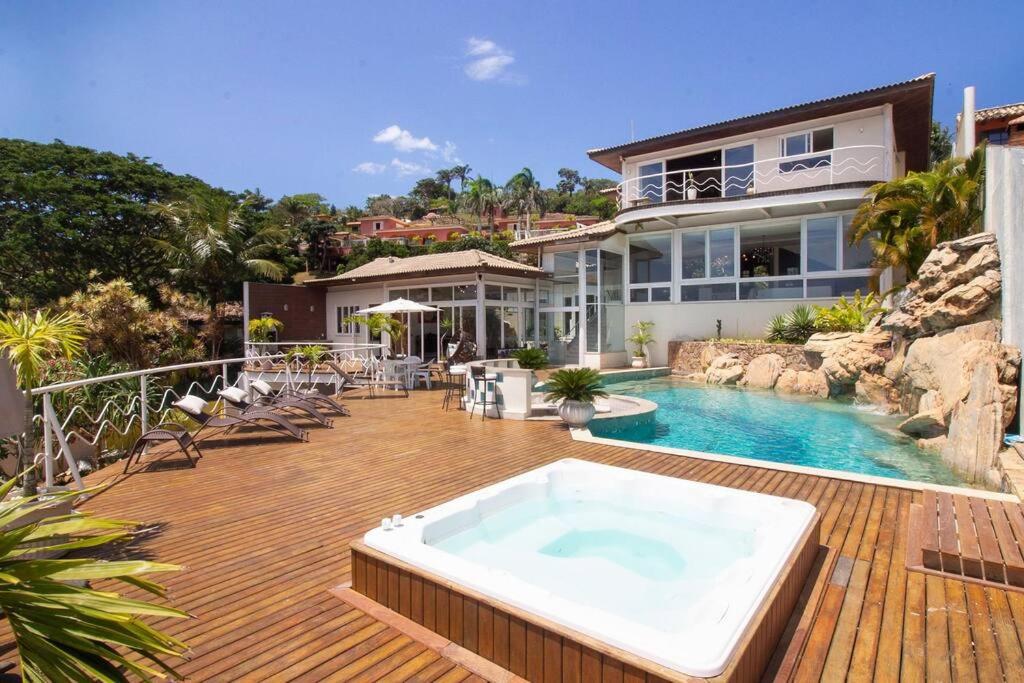 una casa con bañera de hidromasaje en una terraza en Maravilhosa Mansão em Frente à Praia da Ferradura Por Luxury Rentals en Búzios