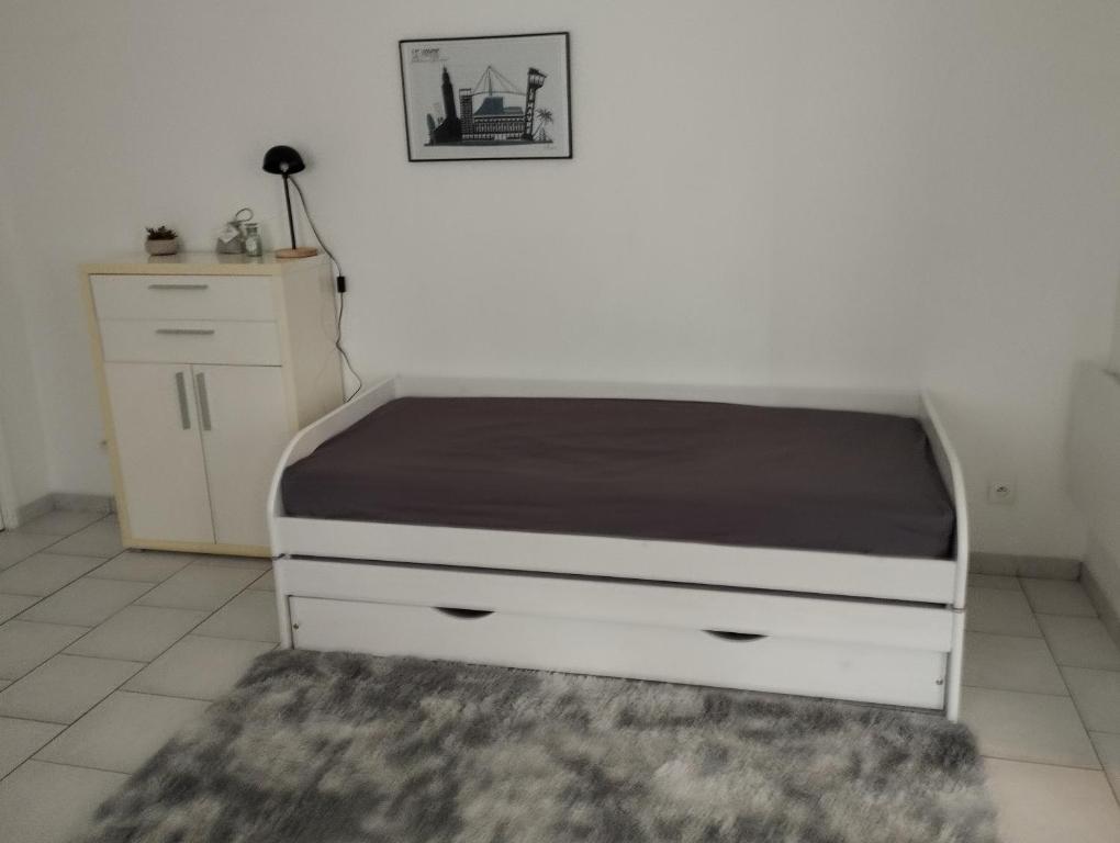 een bed in een kamer met een bedframe en een tapijt bij studio charmant canapé lit Netflix Prime video in Le Havre