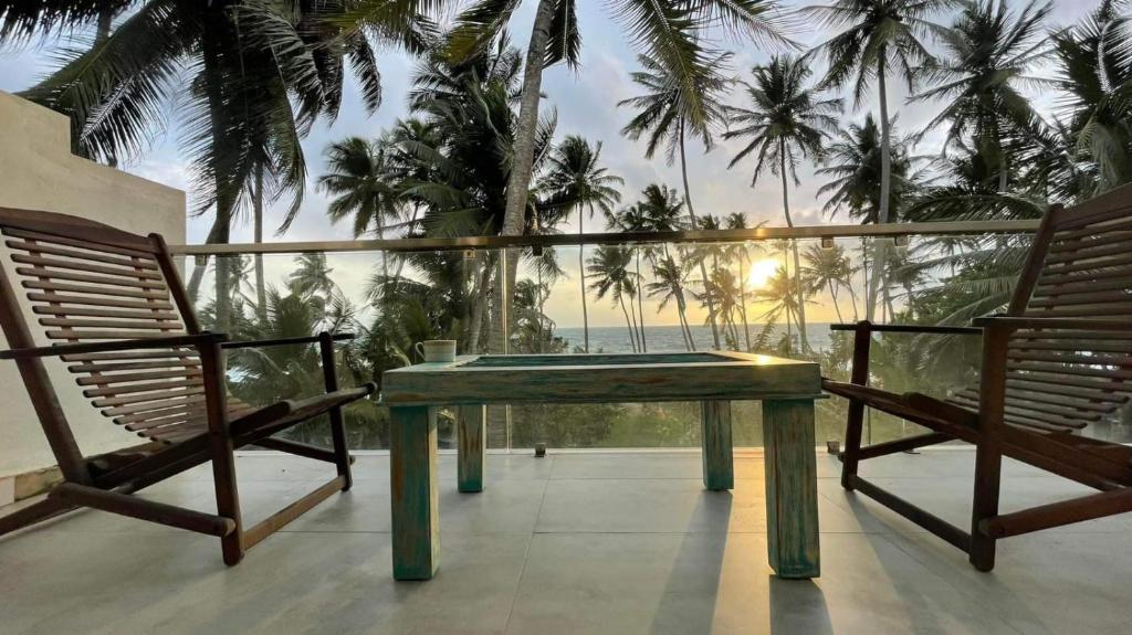 uma mesa e duas cadeiras numa varanda com palmeiras em Villa LA Kurumba em Ambalangoda
