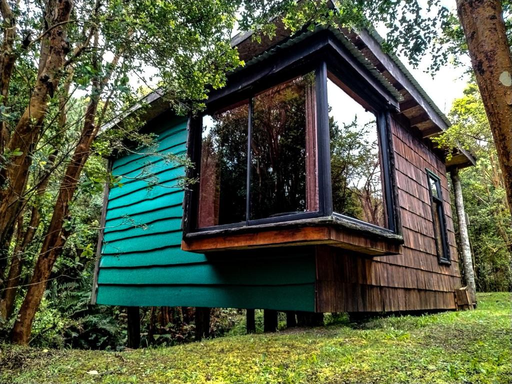 a tree house in the woods with a window at Hostal & Cabañas Luna del Sur in Cucao