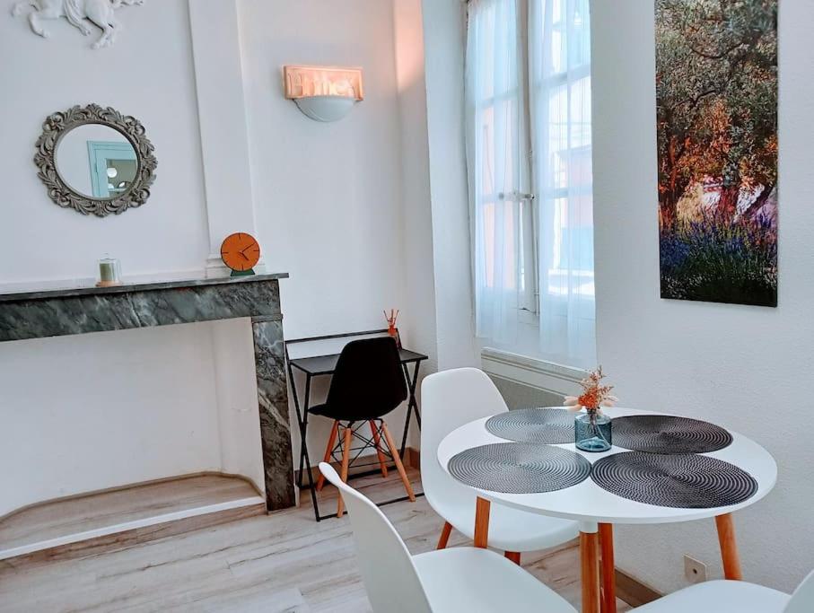 uma sala de estar com uma mesa e cadeiras e uma lareira em Appartement cosy centre-ville. em Perpignan