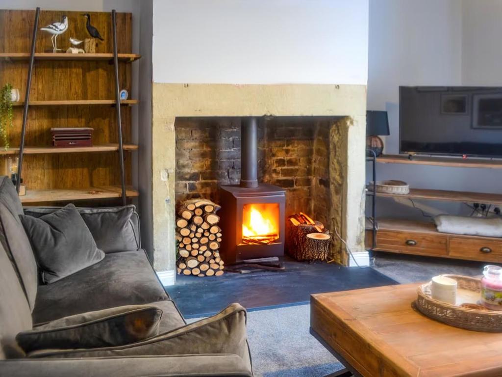 sala de estar con chimenea y sofá en Avocet Cottage Amble, en Amble