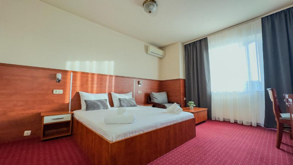 a hotel room with a bed and a large window at Dezudava Family Hotel in Sandanski