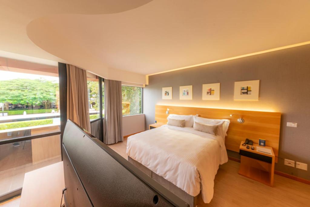 a bedroom with a large bed and a television at Golden Tulip Brasília Alvorada in Brasília