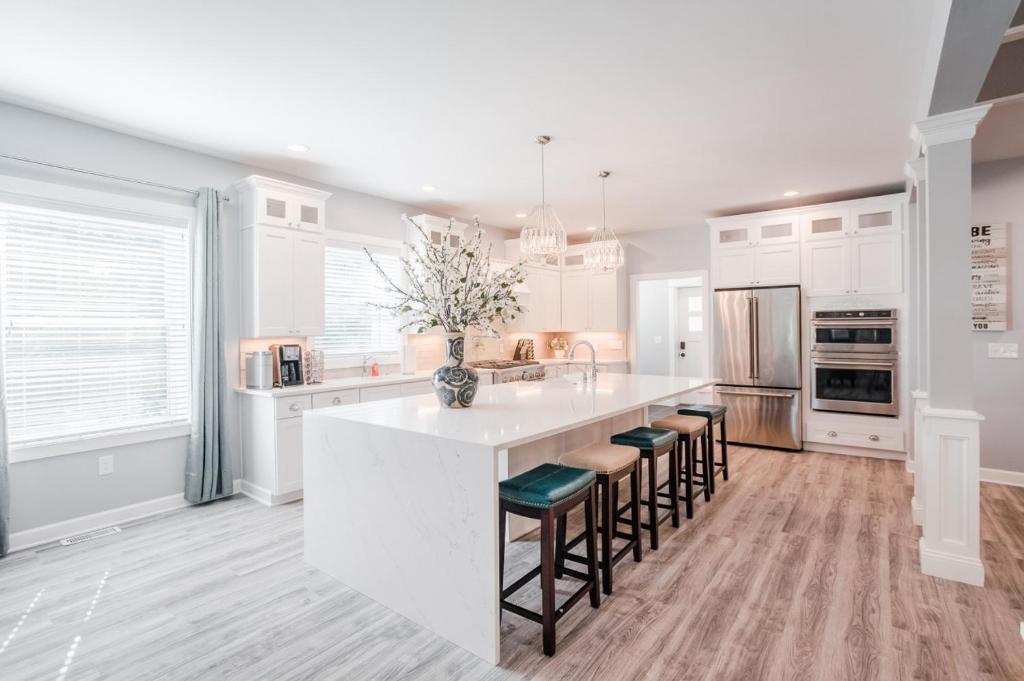 a kitchen with a large white island with bar stools at Glamorous, Upscale 5B Hyde Park Home with Outdoor Patio in Cincinnati