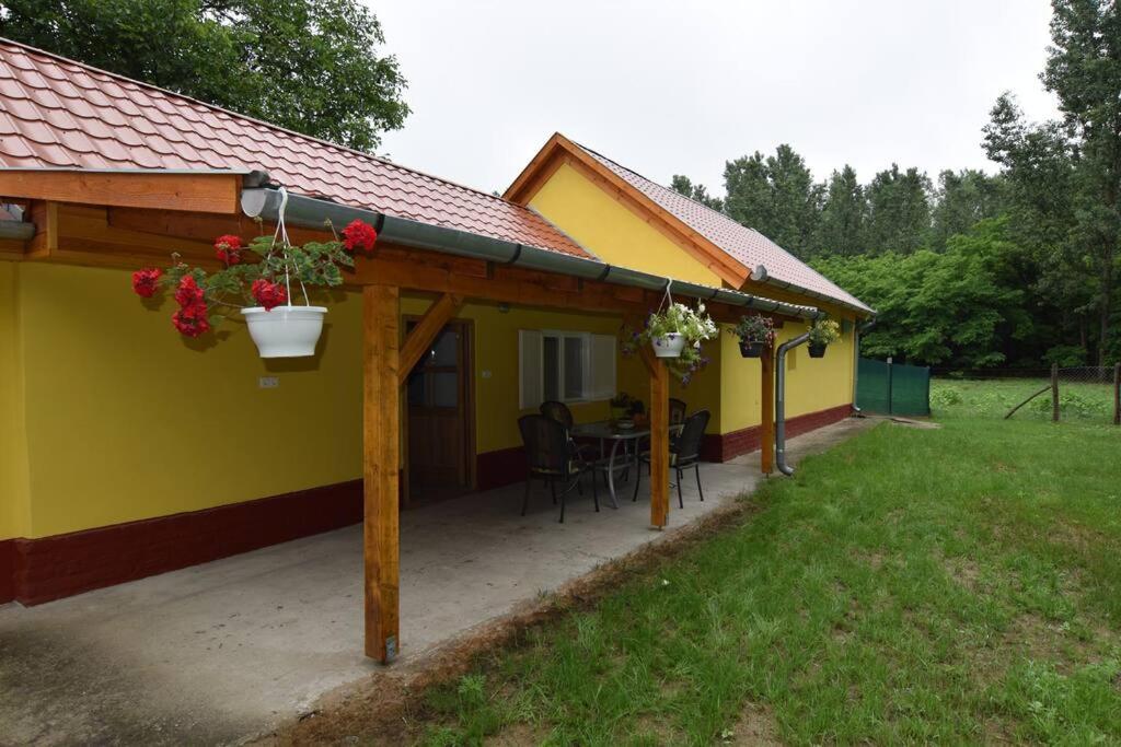 ein gelbes Haus mit einer Terrasse mit einem Tisch in der Unterkunft Béke Tanya Hongarije in Nyársapát