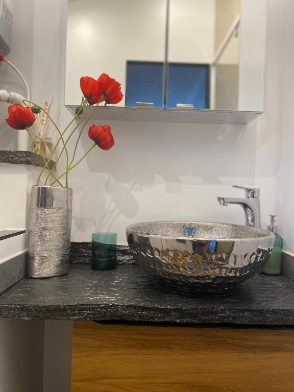 a bathroom counter with a sink and a vase with red roses at Paris-Zénith-bienvenue-terrasse-Netflix in Pantin
