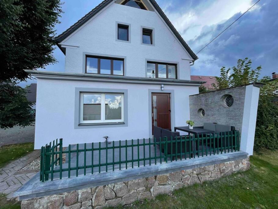 een wit huis met een groen hek ervoor bij Hochwertige Ferienwohnung im Bauernhaus in Freital