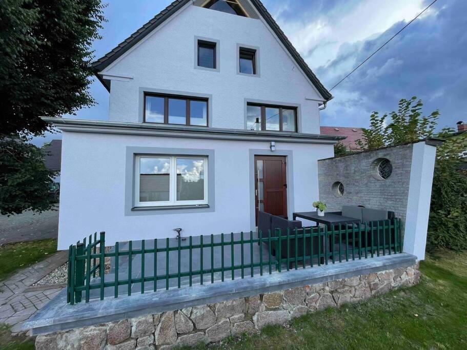 a white house with a green fence in front of it at Hochwertige Ferienwohnung im Bauernhaus in Freital