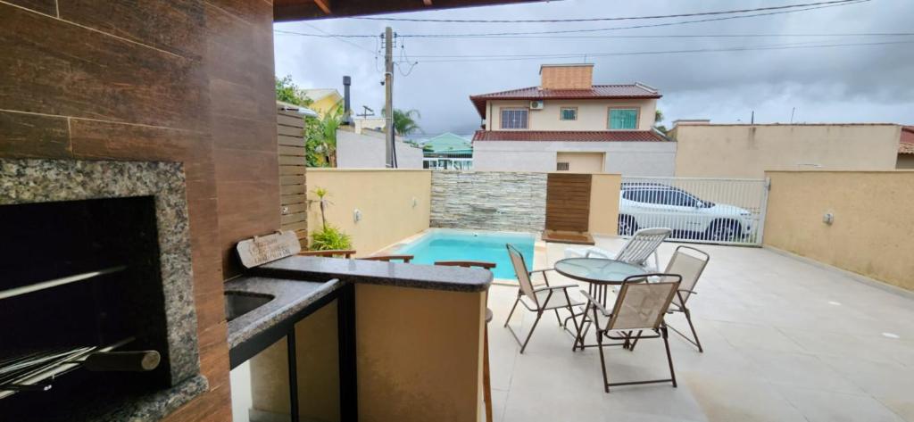 a patio with a table and chairs and a pool at Linda casa no baln. Ponta do papagaio a 100m do mar in Palhoça