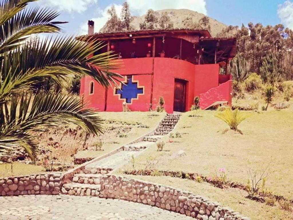 a red building with a blue cross on it at Refugio Samay Toa in Hacienda Gualovi