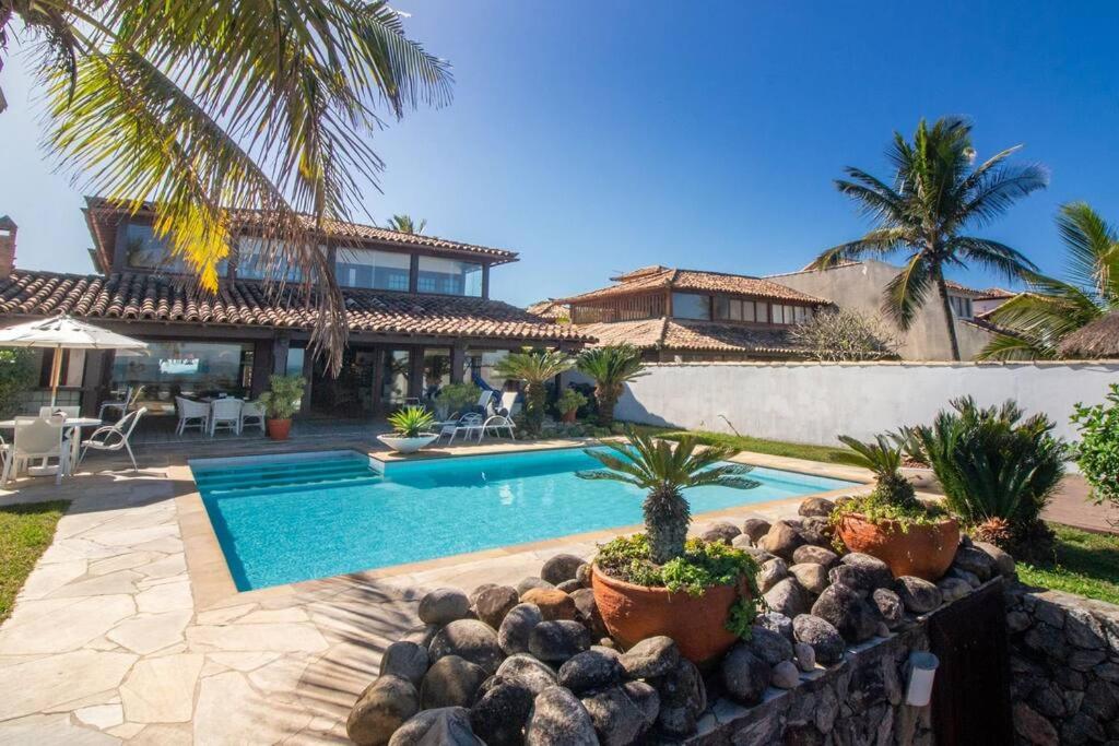 eine Villa mit einem Pool und einem Haus in der Unterkunft Paraíso Pé na Areia de Geribá com Cinco Suítes Por Luxury Rentals in Búzios