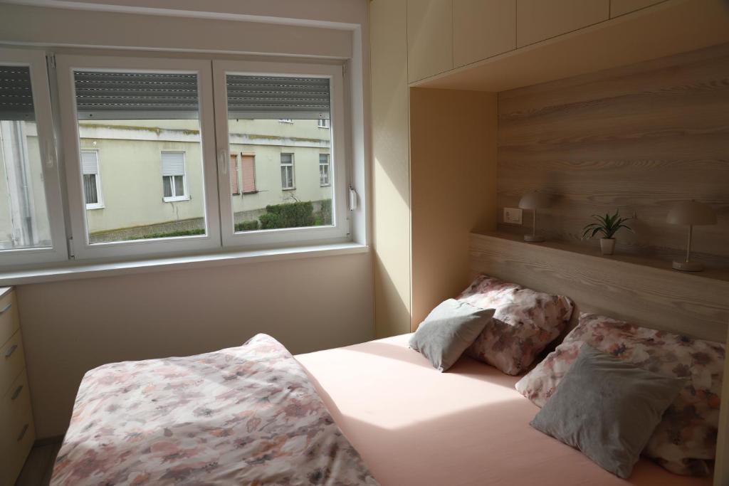 ein Bett in einem Schlafzimmer mit zwei Fenstern in der Unterkunft Apartman Željka in Karlovac