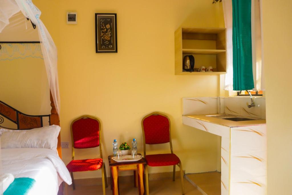 Four Wheels Gardens Hotel & Accommodation في Kitengela : غرفة نوم بها كرسيين وسرير ومكتب