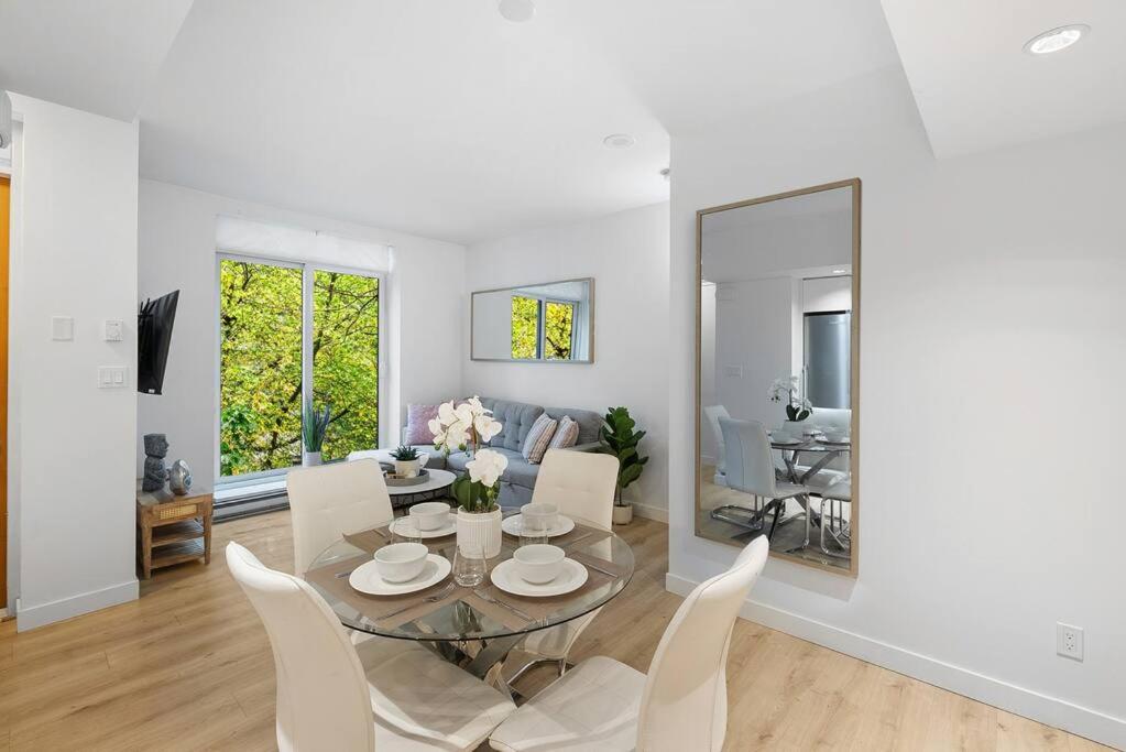 a living room with a glass table and white chairs at Elegant 2-Bedroom Duplex Haven in Vibrant Yaletown in Vancouver