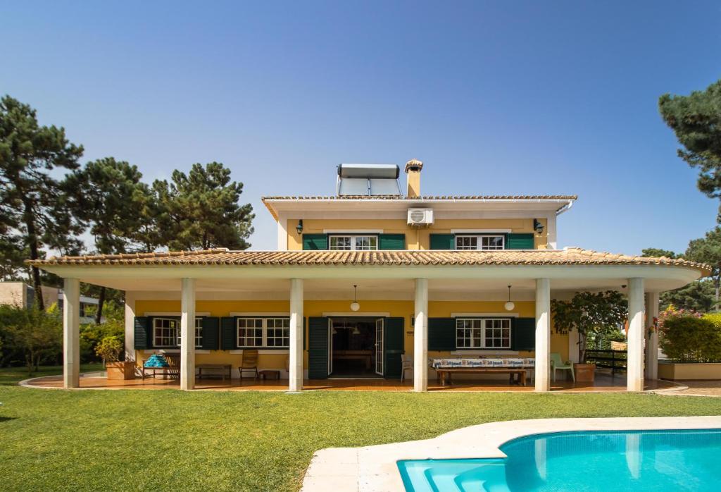 une maison avec une piscine en face de celle-ci dans l'établissement Aroeira Villa - Sea & Golf, à Aroeira