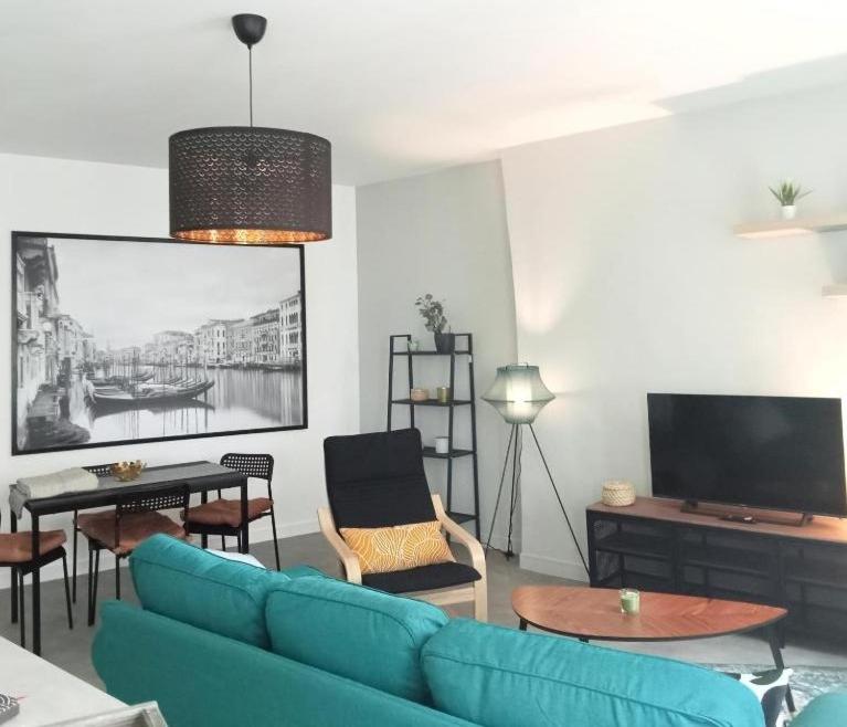 un salon avec un canapé bleu et une télévision dans l'établissement Le Vénitien, à Saint-Étienne