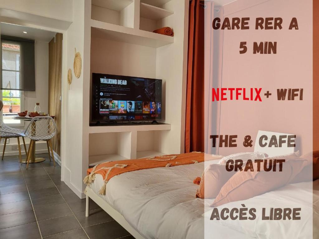 Habitación con cama y TV en la pared. en Appart' Terracotta - Champs Élysées 20 mn - JO 2024, en Maisons-Laffitte